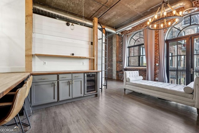 living area with baseboards, brick wall, a chandelier, a fireplace, and wood finished floors