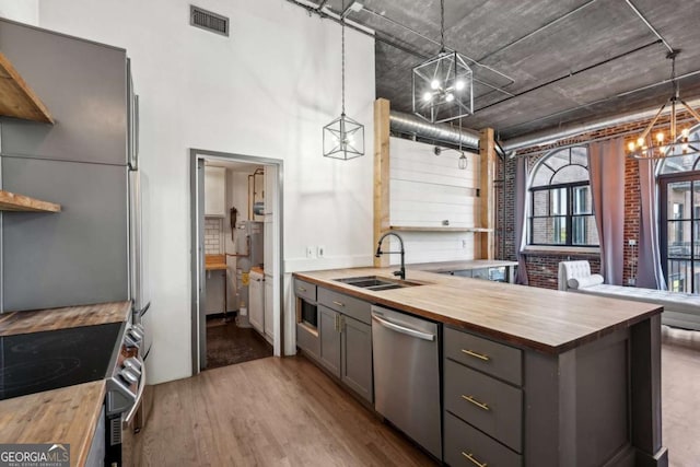 kitchen featuring wine cooler, wood counters, freestanding refrigerator, and a sink