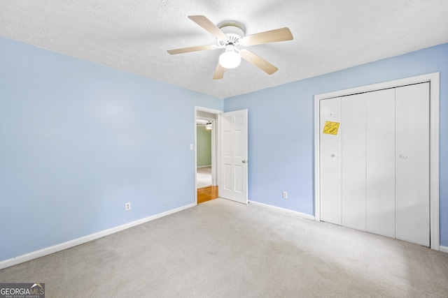 unfurnished bedroom featuring ceiling fan, a textured ceiling, a closet, carpet floors, and baseboards