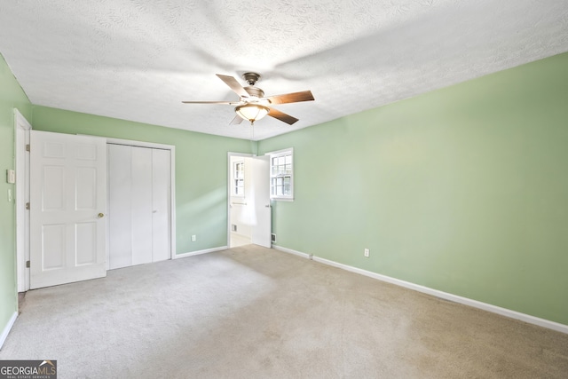 unfurnished bedroom featuring a textured ceiling, a closet, carpet flooring, and baseboards