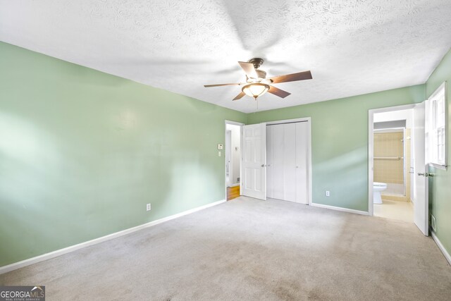 unfurnished bedroom featuring carpet, ensuite bath, a closet, and baseboards