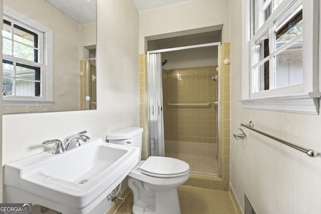 full bathroom with toilet, a stall shower, a sink, and a textured ceiling