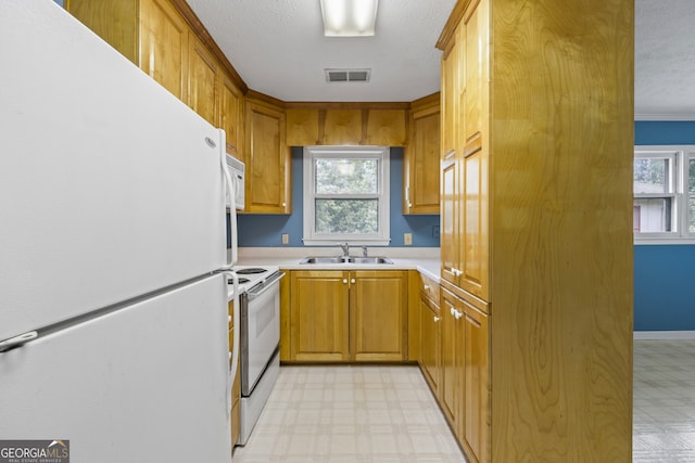 kitchen with white appliances, light countertops, visible vents, light floors, and a sink