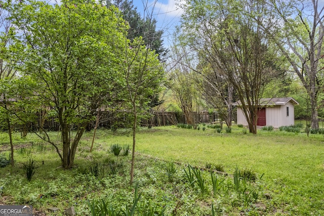 view of yard with a storage shed, fence, and an outbuilding