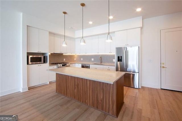 kitchen with stainless steel appliances, light wood finished floors, a sink, and a kitchen island