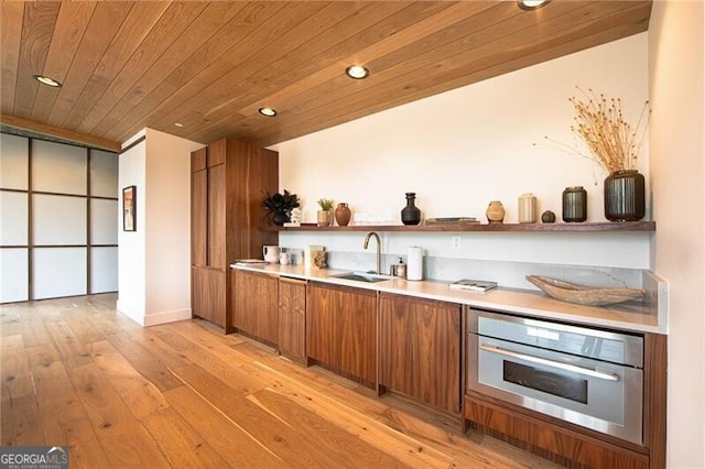 kitchen with a sink, open shelves, brown cabinetry, stainless steel oven, and wooden ceiling