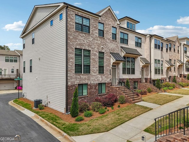 townhome / multi-family property with brick siding and cooling unit
