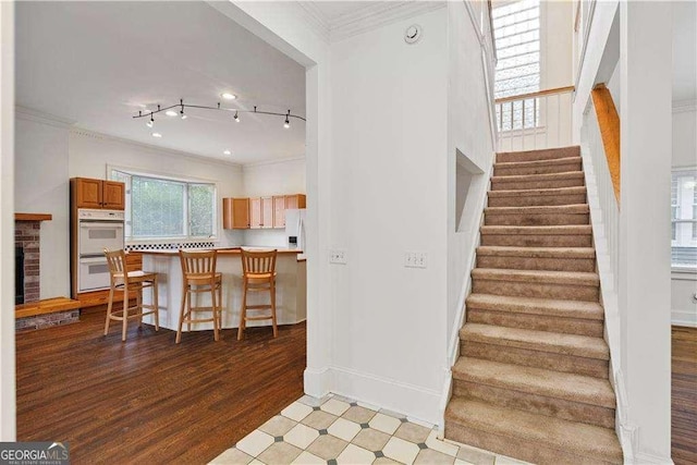 873 Monroe Cir NE, Atlanta, GA 30308 - staircase featuring track lighting, baseboards, a brick fireplace, crown molding, and wood finished floors