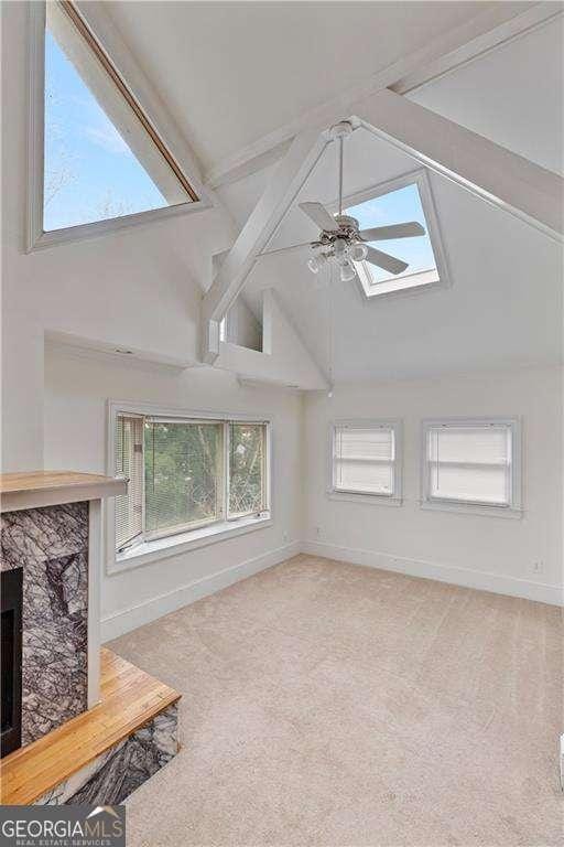 873 Monroe Cir NE, Atlanta, GA 30308 - carpeted living room with baseboards, a ceiling fan, beam ceiling, a skylight, and high vaulted ceiling