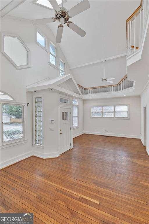 873 Monroe Cir NE, Atlanta, GA 30308 - unfurnished living room with hardwood / wood-style floors, a healthy amount of sunlight, high vaulted ceiling, and a ceiling fan