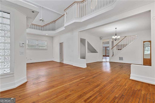 873 Monroe Cir NE, Atlanta, GA 30308 - unfurnished living room featuring ornamental molding, visible vents, a high ceiling, wood-type flooring, and baseboards
