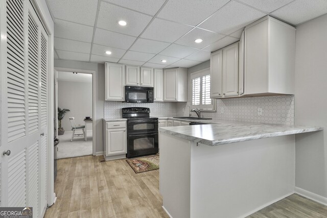 31 Festiva Dr, Newnan, GA 30263 - kitchen featuring a sink, light countertops, light wood-style floors, a peninsula, and black appliances