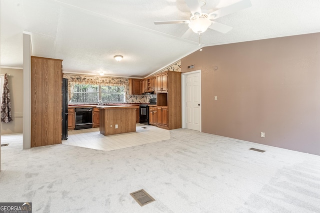 kitchen with brown cabinets, vaulted ceiling, light carpet, a center island, and black appliances