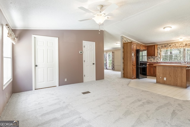 kitchen with a textured ceiling, brown cabinetry, open floor plan, light colored carpet, and freestanding refrigerator