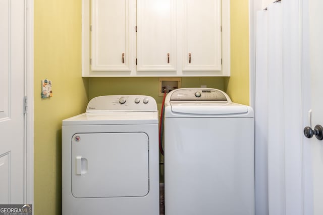 clothes washing area featuring washing machine and dryer and cabinet space