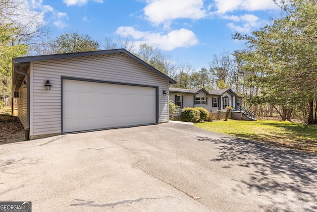 ranch-style house featuring a front lawn, aphalt driveway, and a garage