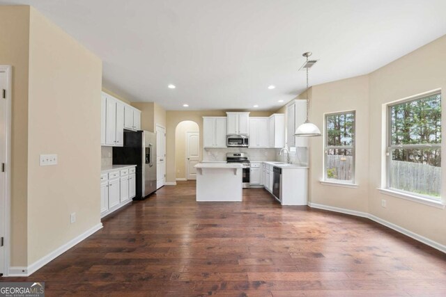 3892 Trillium Wood Trl, Snellville, GA 30039 - kitchen with appliances with stainless steel finishes, arched walkways, a center island, dark wood-style flooring, and white cabinets