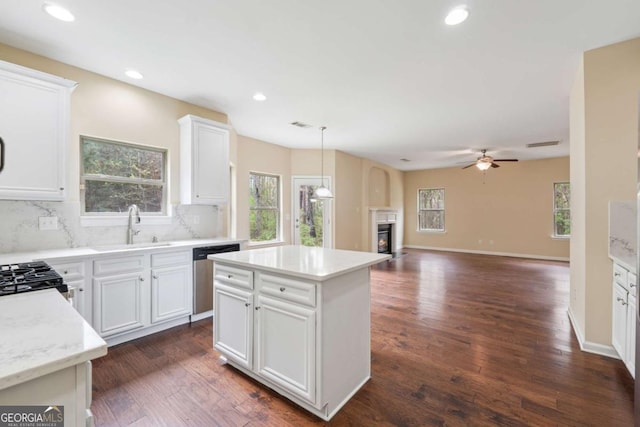 3892 Trillium Wood Trl, Snellville, GA 30039 - kitchen featuring stainless steel dishwasher, a glass covered fireplace, decorative backsplash, dark wood-style flooring, and recessed lighting