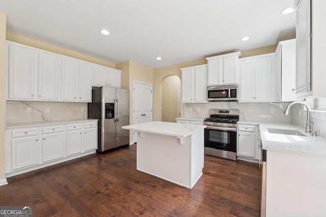 3892 Trillium Wood Trl, Snellville, GA 30039 - kitchen featuring appliances with stainless steel finishes, arched walkways, decorative backsplash, a center island, and white cabinetry