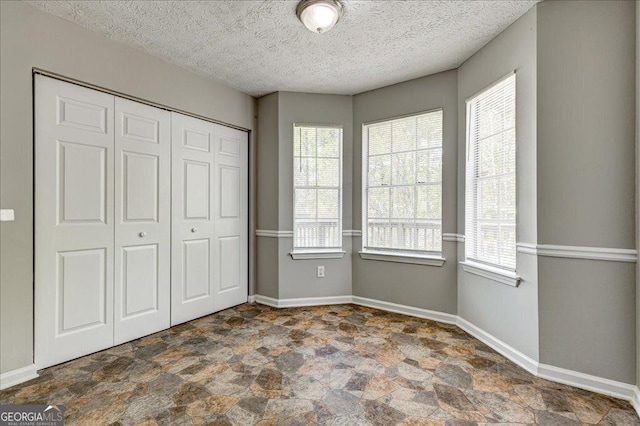 3612 River Mill Ct, Ellenwood, GA 30294 - unfurnished bedroom with stone finish flooring, a closet, baseboards, and a textured ceiling