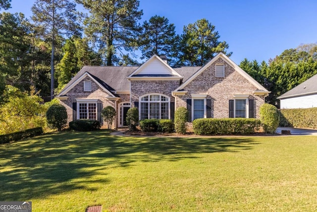 view of front facade with brick siding and a front lawn