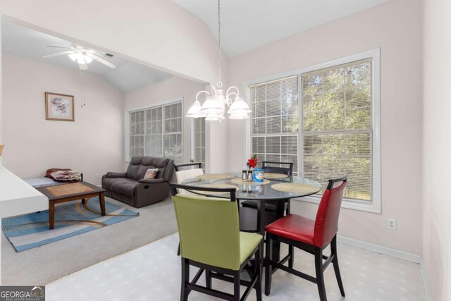 carpeted dining area with ceiling fan with notable chandelier, baseboards, and lofted ceiling