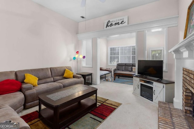 living room with a fireplace, carpet, visible vents, and ceiling fan