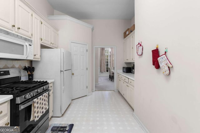 kitchen with white cabinets, white microwave, stainless steel gas stove, and light countertops