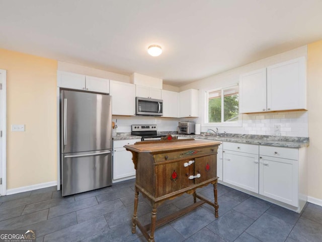 244 Sherwood Ln, Brunswick, GA 31525 - kitchen featuring stainless steel appliances, white cabinetry, decorative backsplash, and dark tile patterned floors
