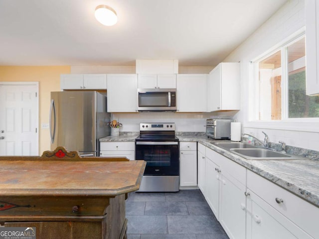 244 Sherwood Ln, Brunswick, GA 31525 - kitchen featuring stainless steel appliances, white cabinets, decorative backsplash, and dark tile patterned flooring