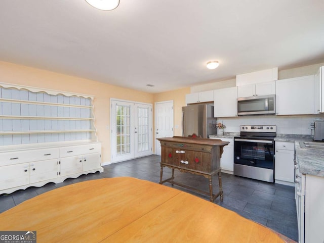 244 Sherwood Ln, Brunswick, GA 31525 - kitchen with appliances with stainless steel finishes, dark tile patterned floors, white cabinetry, and backsplash