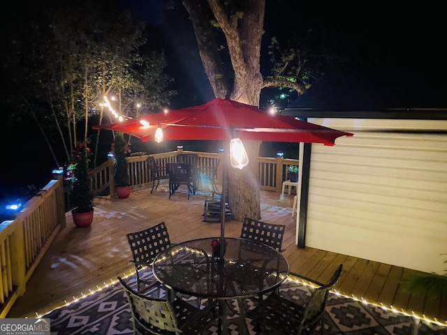 patio at night with a deck and outdoor dining area
