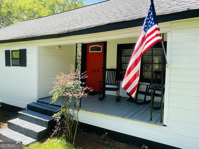 property entrance featuring roof with shingles and a porch