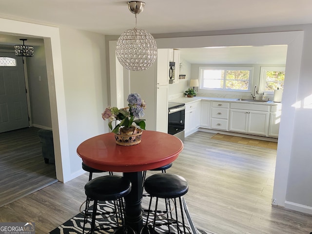 dining space with baseboards, an inviting chandelier, and light wood-type flooring