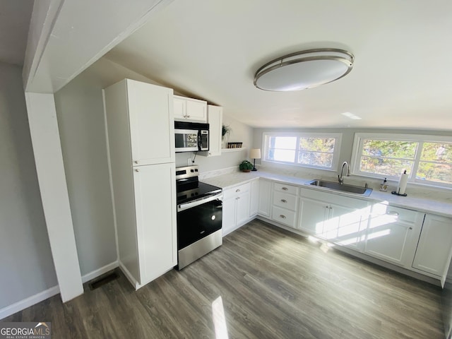kitchen with appliances with stainless steel finishes, a sink, light countertops, dark wood-style floors, and white cabinetry