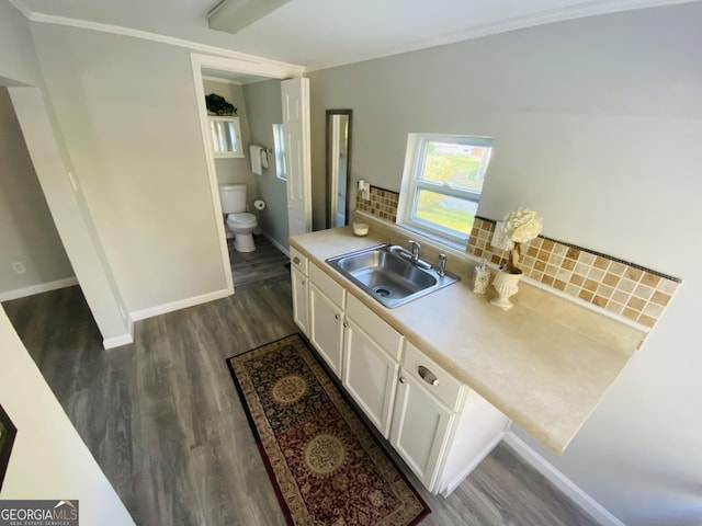 kitchen with backsplash, dark wood-style flooring, a sink, light countertops, and white cabinets