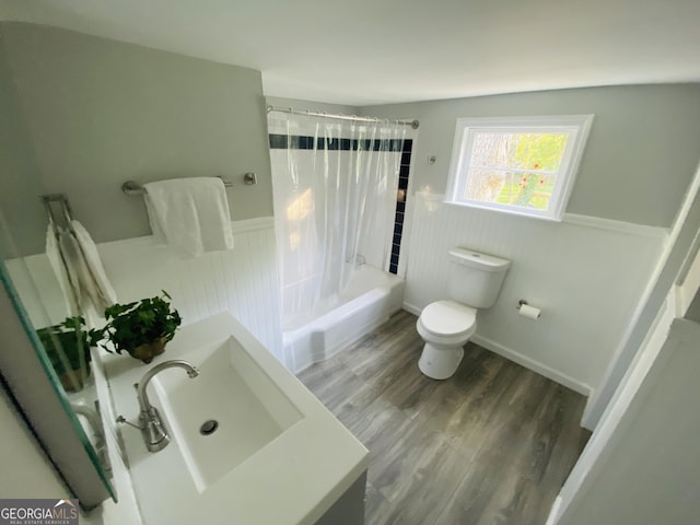 full bathroom with wainscoting, wood finished floors, shower / tub combo, vanity, and toilet