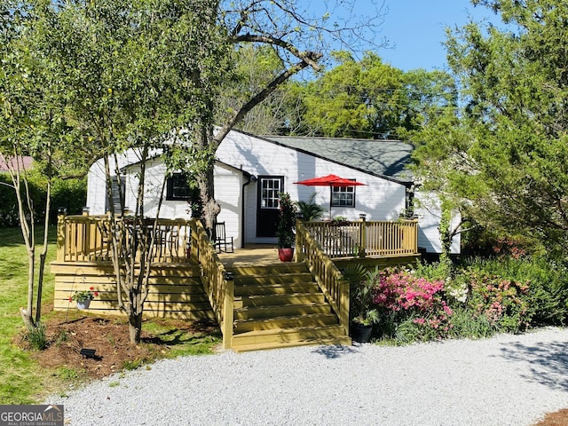 bungalow-style home with a shingled roof, a deck, and stairway