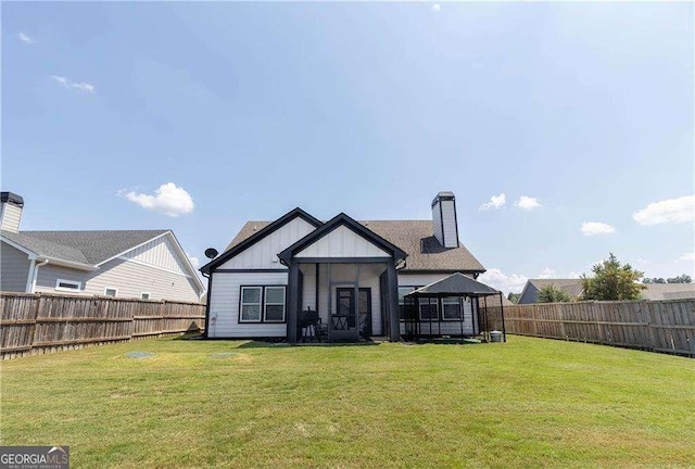 back of property featuring board and batten siding, a fenced backyard, a gazebo, and a yard