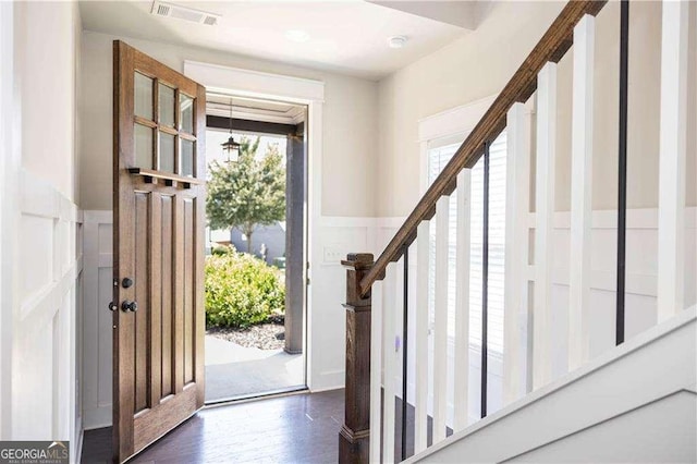 entrance foyer featuring dark wood-style flooring, stairs, visible vents, wainscoting, and a decorative wall