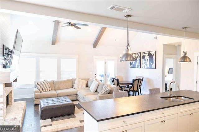 interior space with wood finished floors, beamed ceiling, a ceiling fan, and visible vents