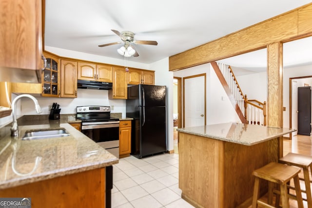 kitchen featuring stainless steel range with electric stovetop, a sink, freestanding refrigerator, a ceiling fan, and under cabinet range hood