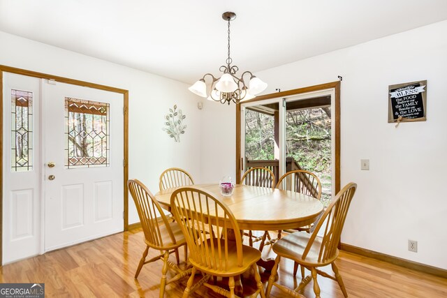 dining space with a chandelier, light wood-type flooring, and baseboards
