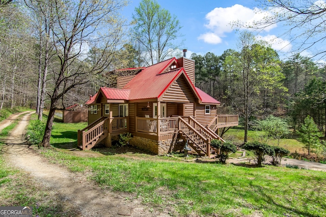 exterior space with metal roof, a chimney, stairs, a front lawn, and a wooden deck