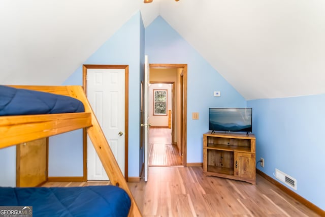 bedroom featuring light wood-style floors, visible vents, baseboards, and lofted ceiling