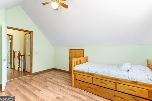 bedroom with light wood-style flooring, a ceiling fan, vaulted ceiling, and baseboards