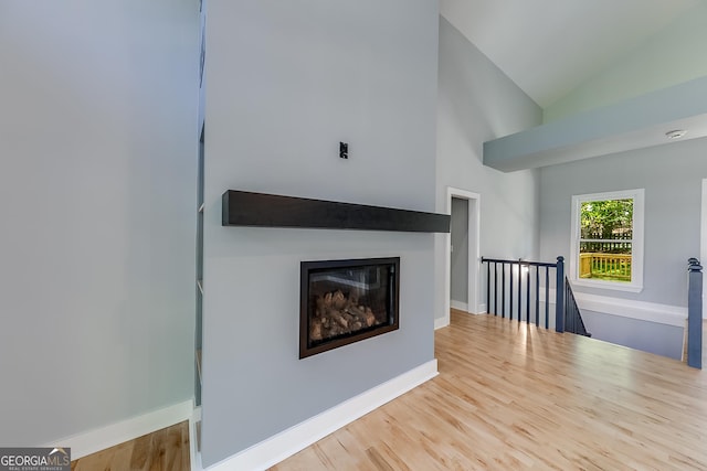 1762 Green Rd, Buford, GA 30518 - unfurnished living room with high vaulted ceiling, a glass covered fireplace, baseboards, and wood finished floors