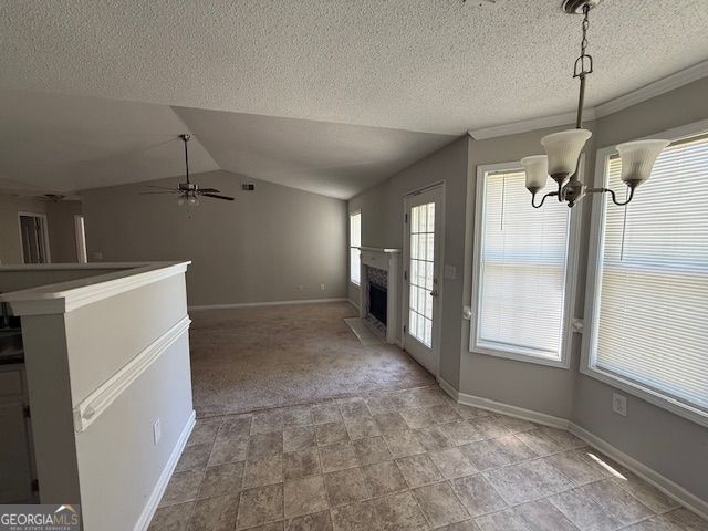 interior space featuring a textured ceiling, ceiling fan with notable chandelier, baseboards, and vaulted ceiling