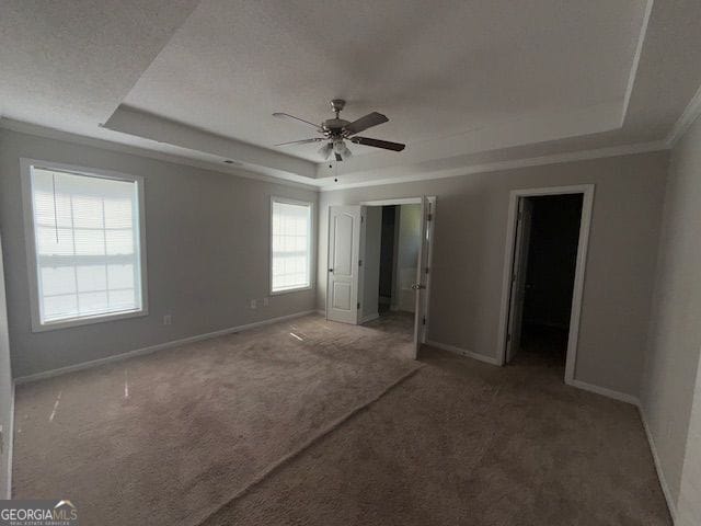 unfurnished bedroom featuring baseboards, ornamental molding, a raised ceiling, carpet floors, and ceiling fan