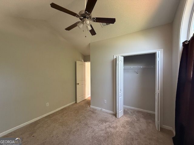 unfurnished bedroom featuring carpet, a closet, a ceiling fan, lofted ceiling, and baseboards